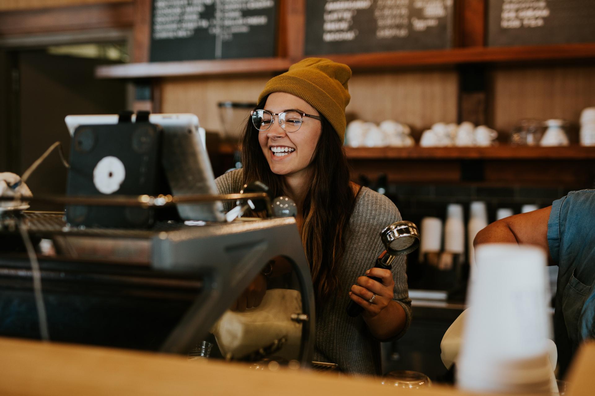 Barista sonriendo detrás de mostrador de cafetería