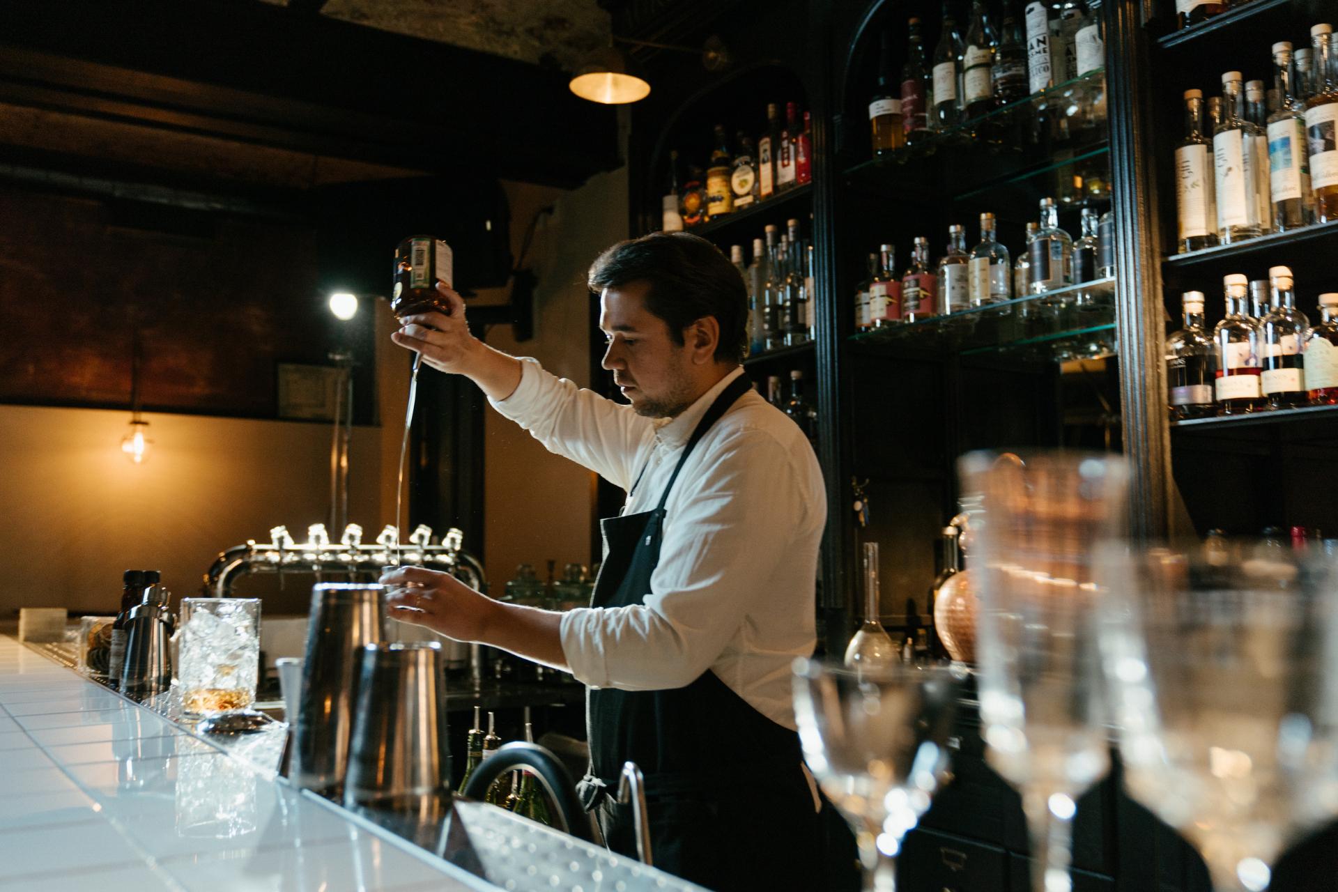 Bartender ahli menuangkan minuman di bar