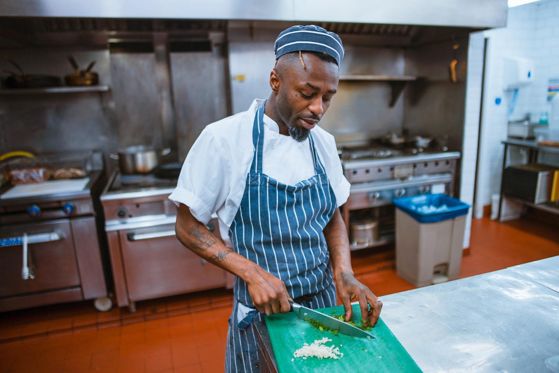 Cook cutting vegetables in restaurant kitchen