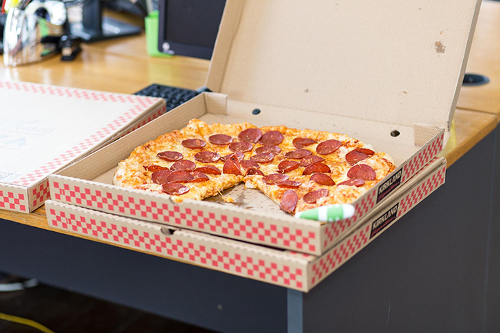 caja de pizza sobre una mesa, con una pizza con un pedazo faltante