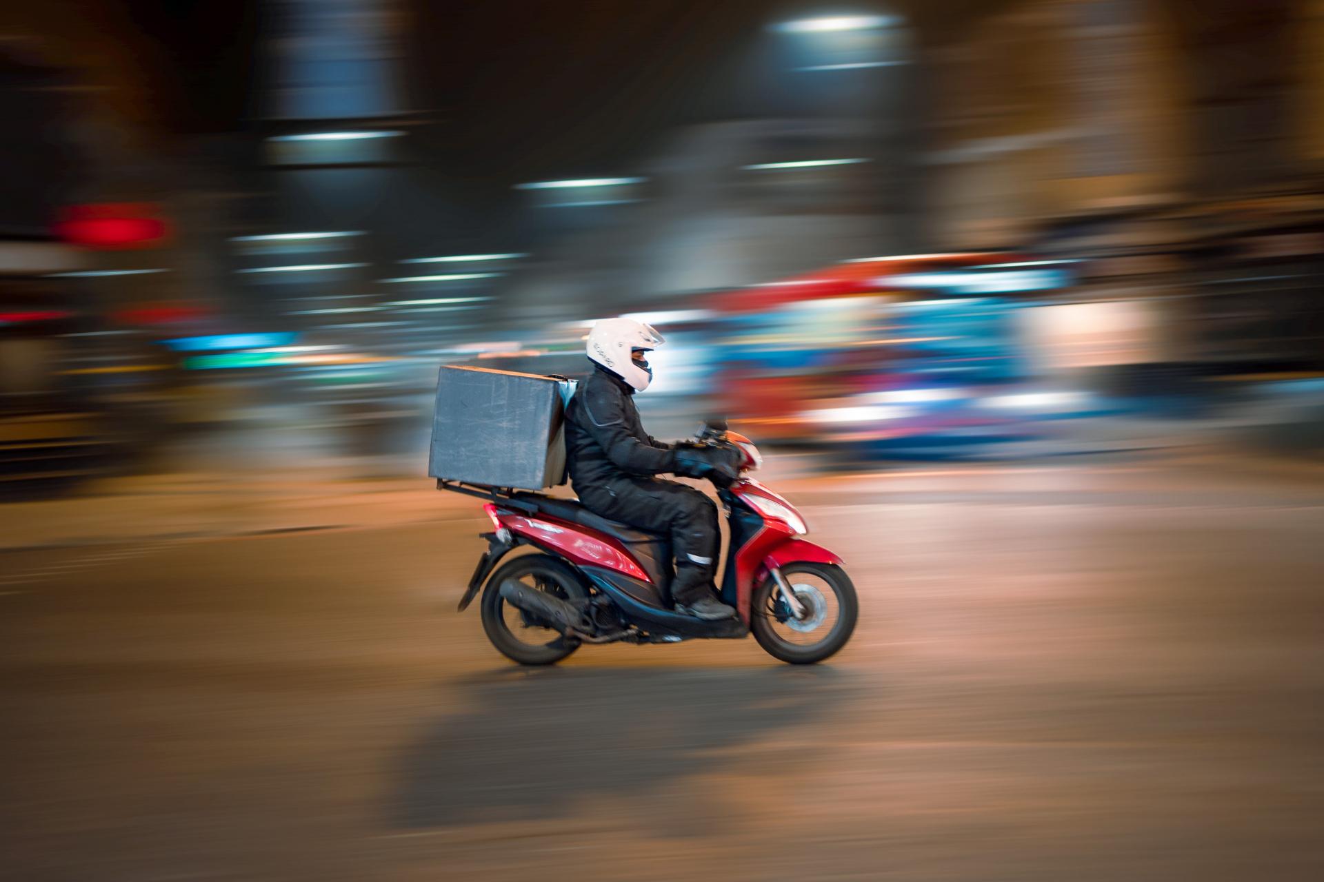 ragazzo delle consegne su una vespa che attraversa la città