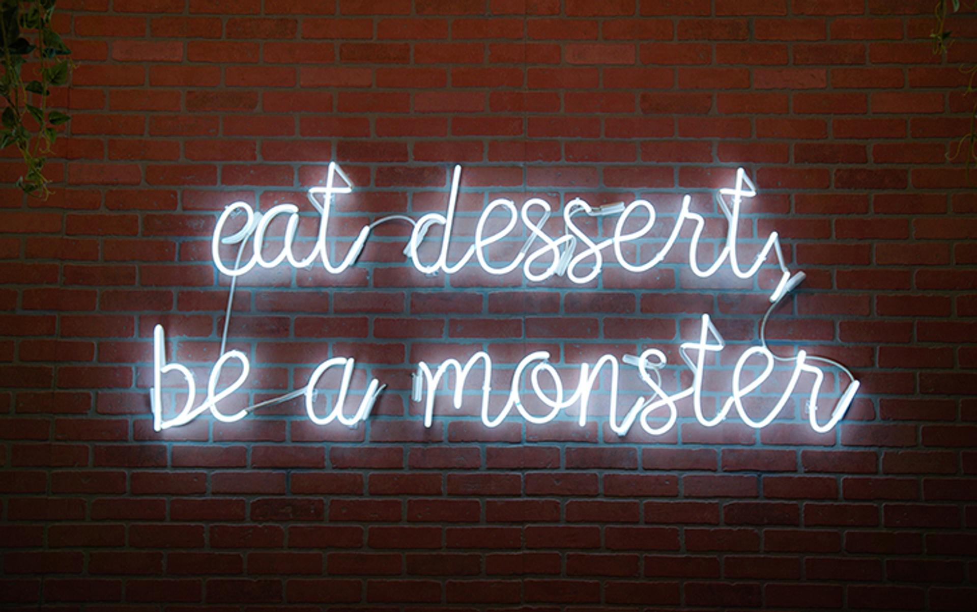 pared con letras luminosas que dicen come postre y sé un monstruo