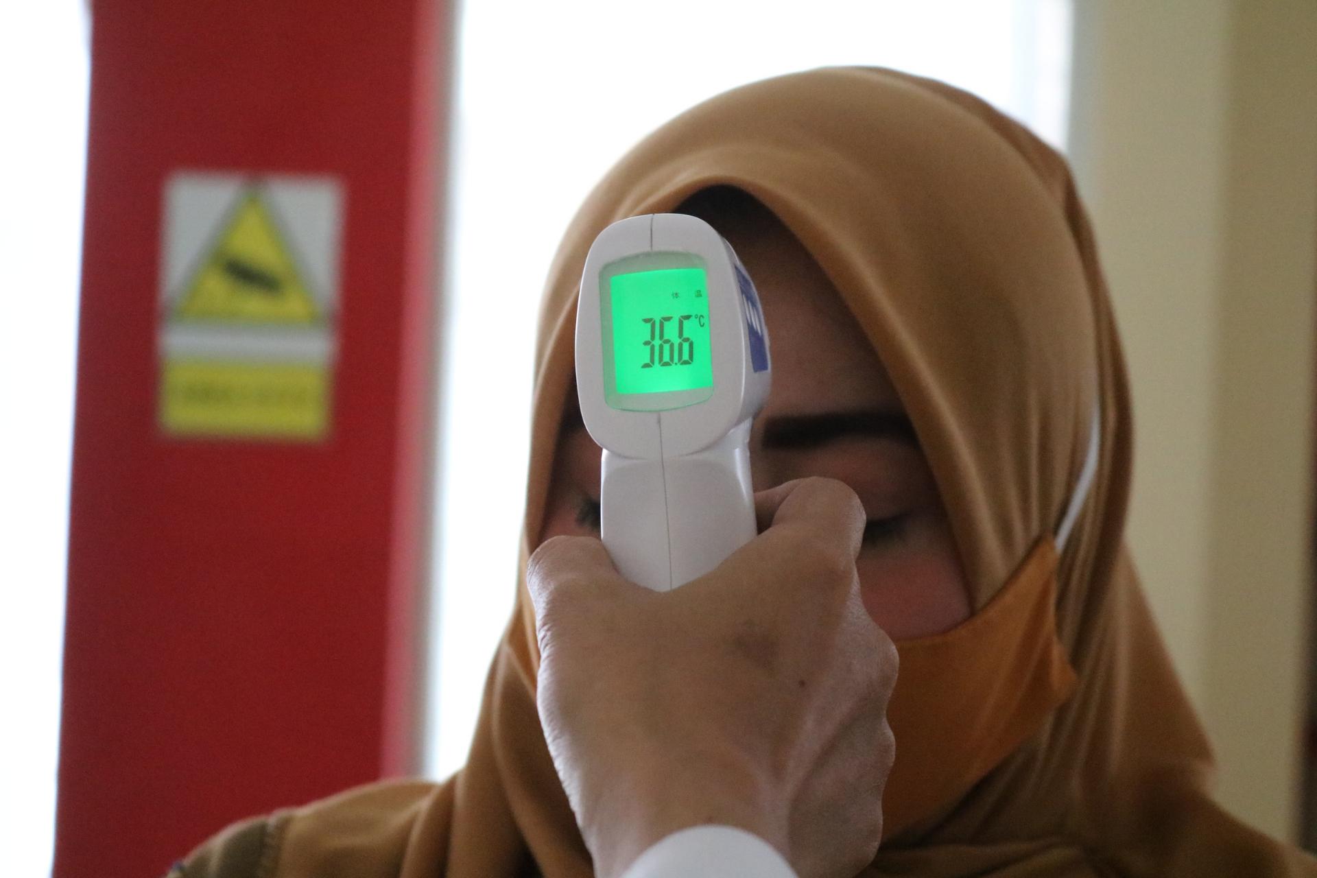 Persona que mide la temperatura de la mujer con termómetro electrónico