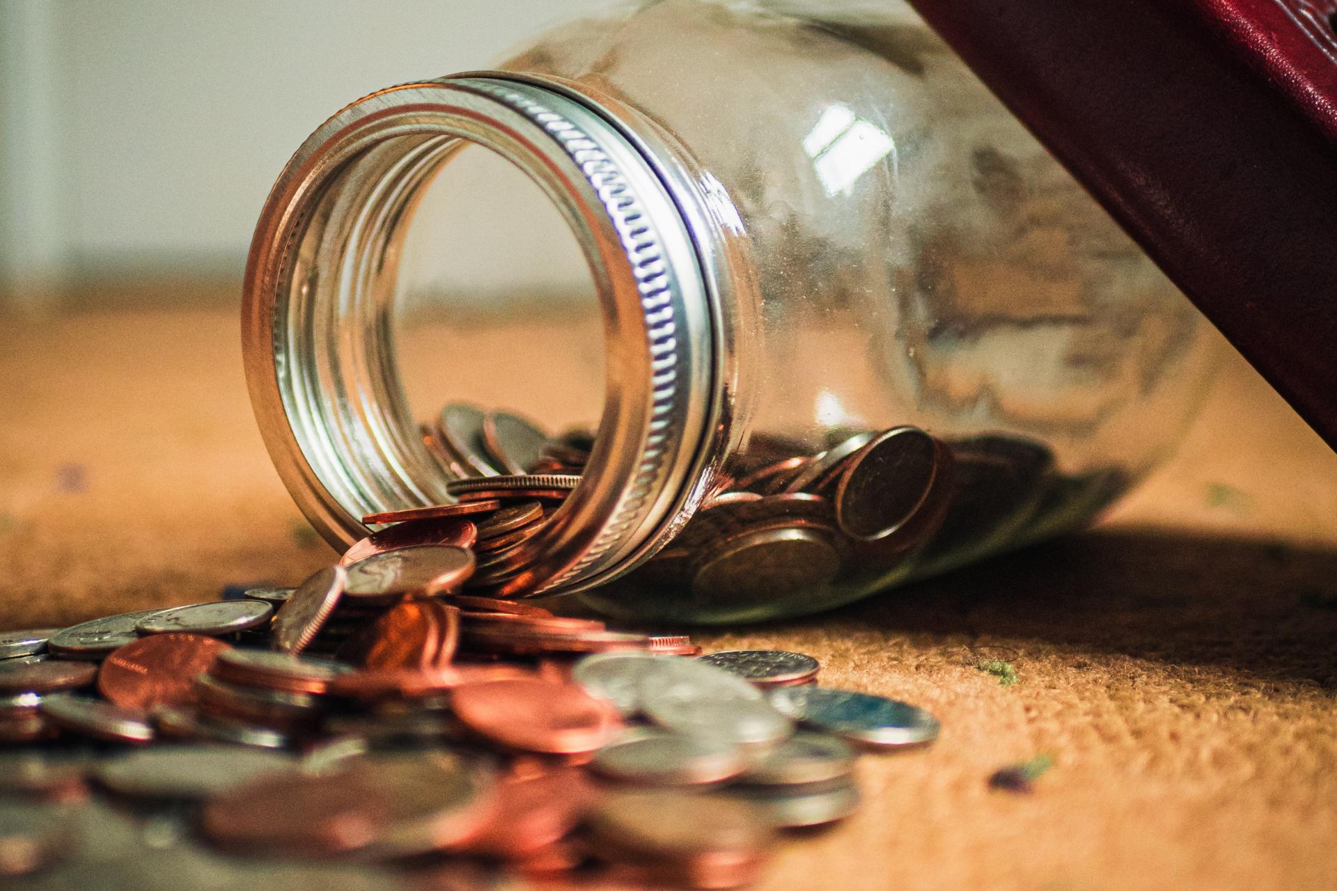 frasco volcado con muchas monedas sobre una mesa