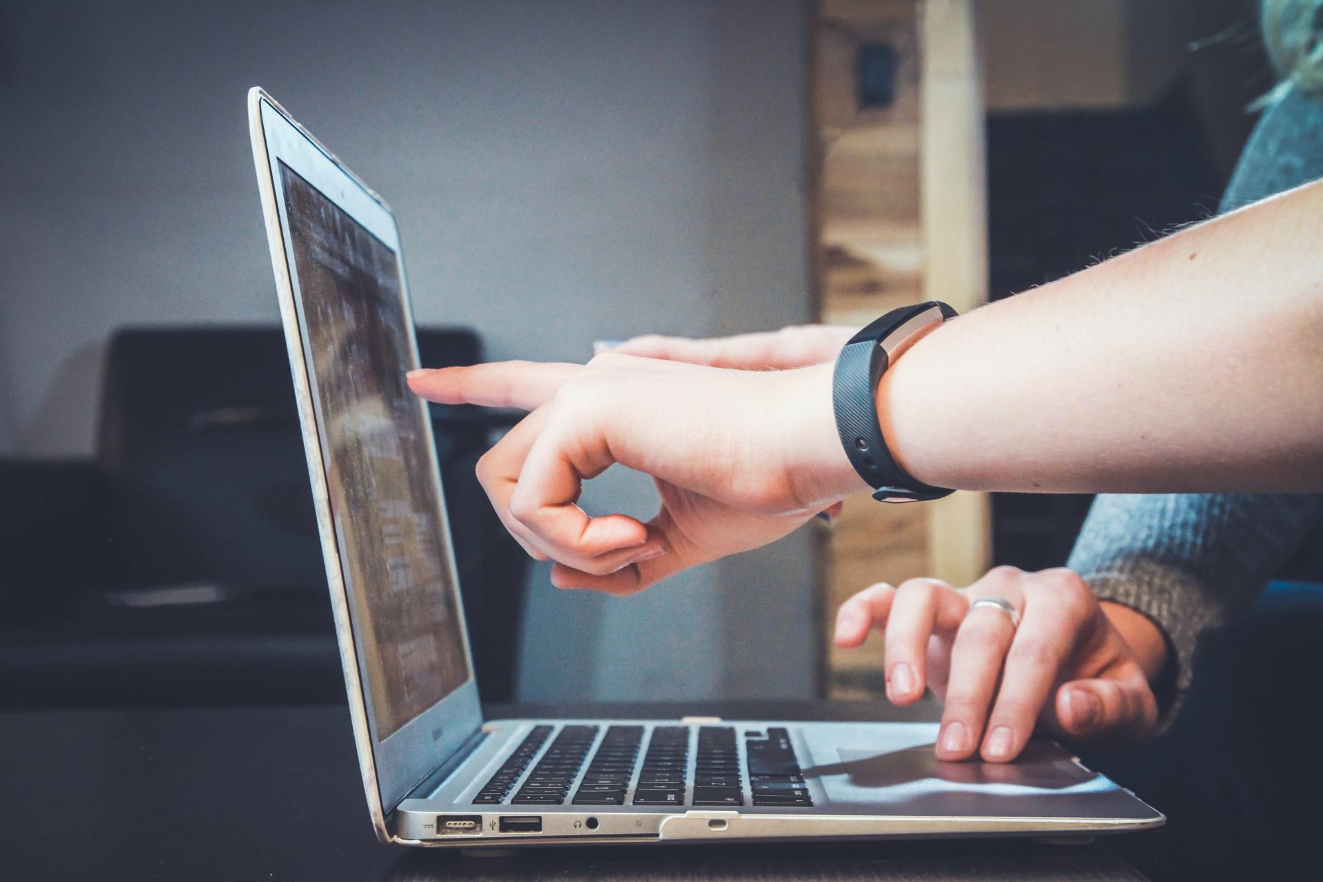 People looking and pointing at something on a laptop screen