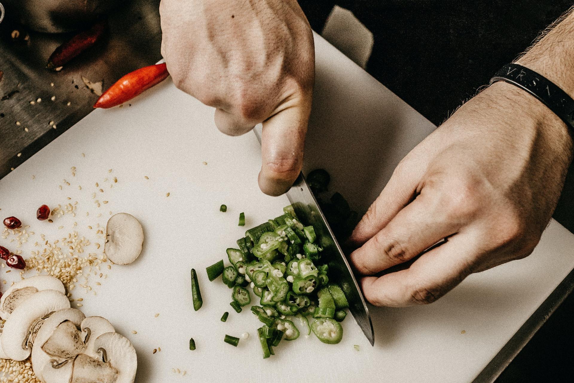Chef cortando vegetales sobre tabla de cortar con cuchillo santoku