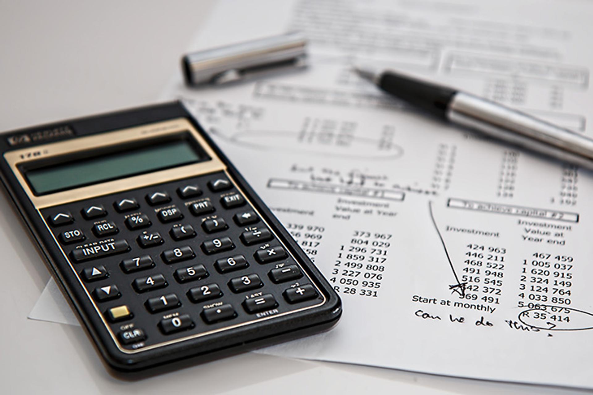 costos, calculo de presupuesto, y otros gastos del restaurante en una hoja de papel, con una calculadora al lado