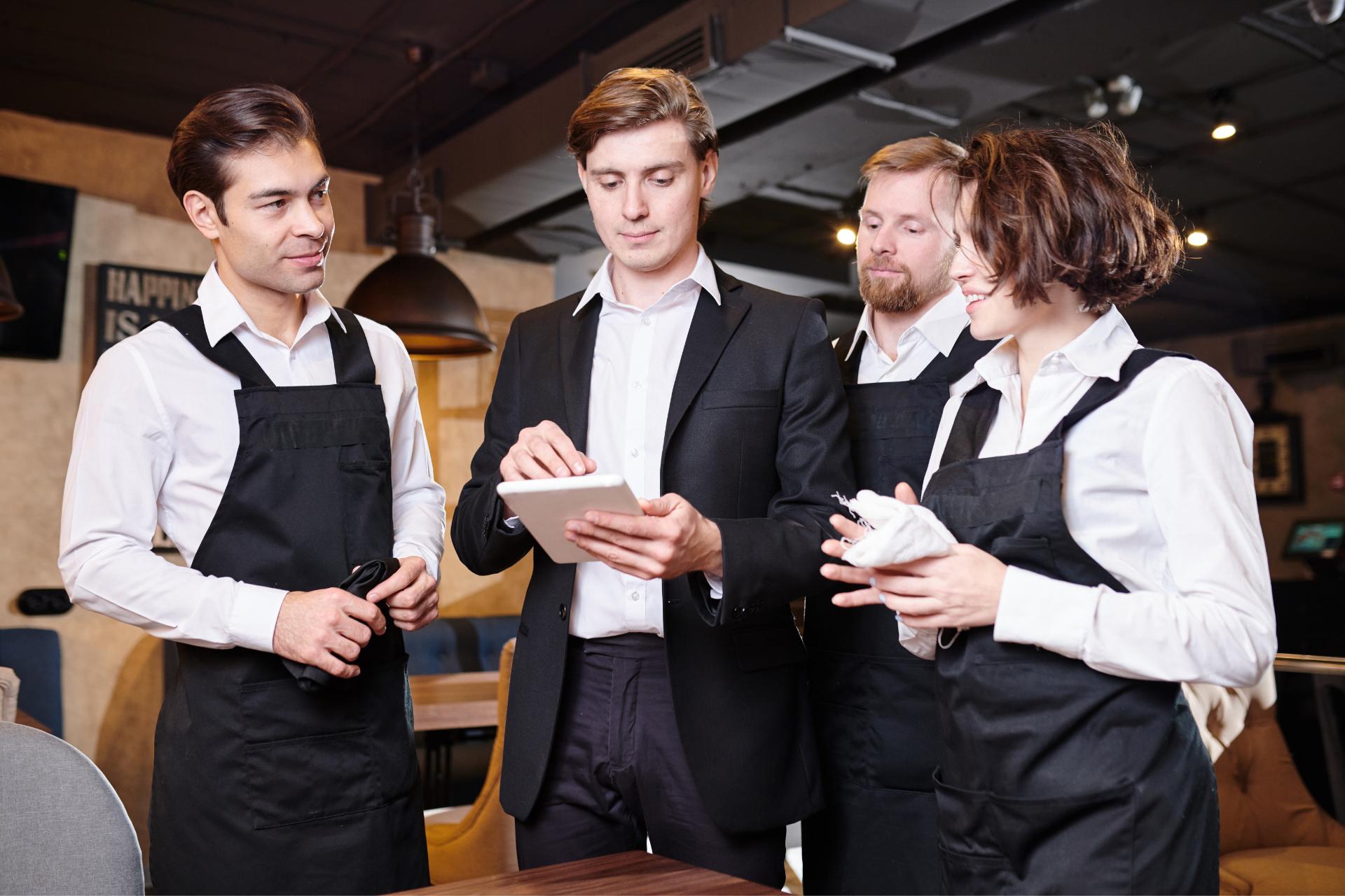 Restaurantmanager in gesprek met obers en leiding geven aan de service