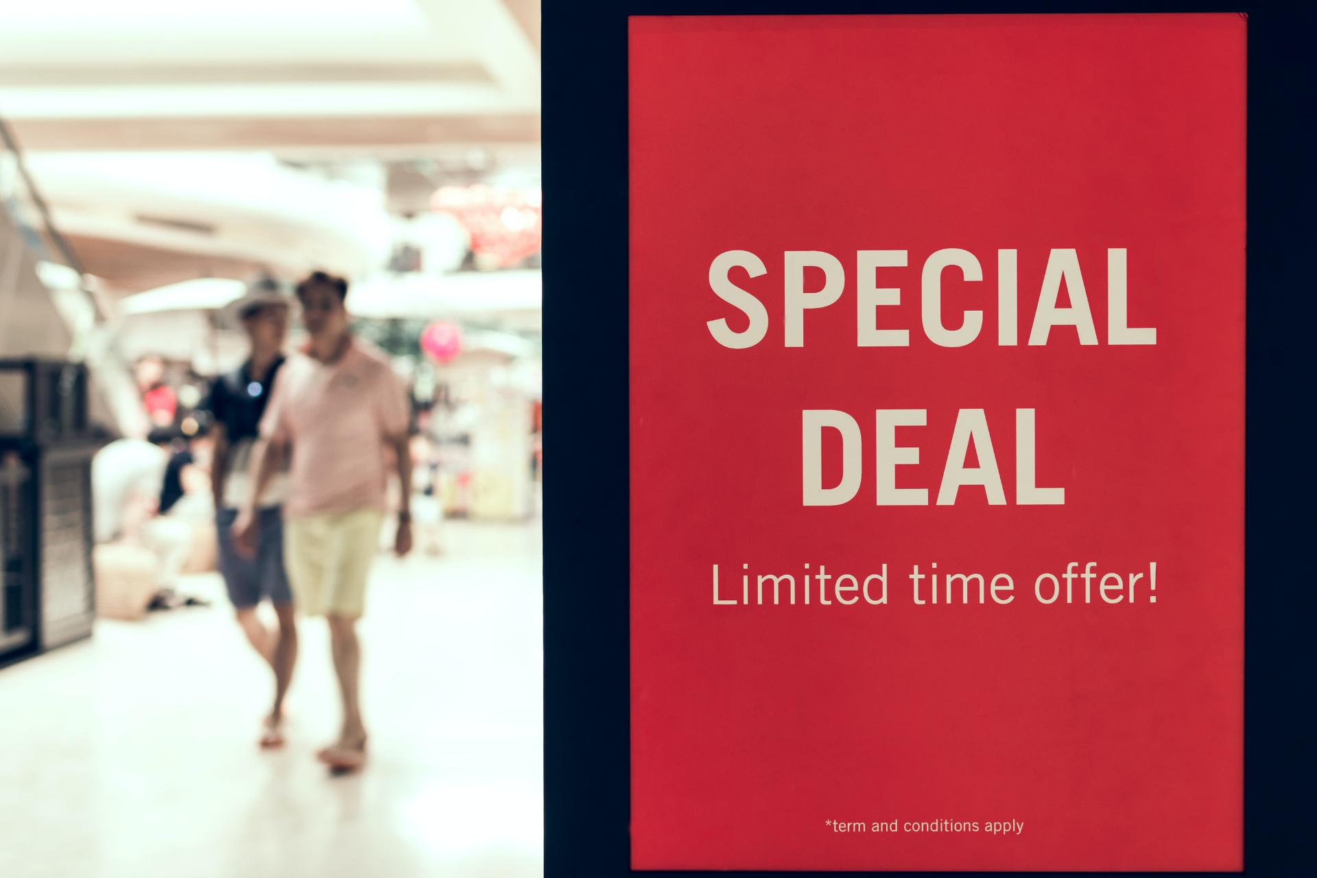 Special deal and limited offer sign on door and people walking in the background