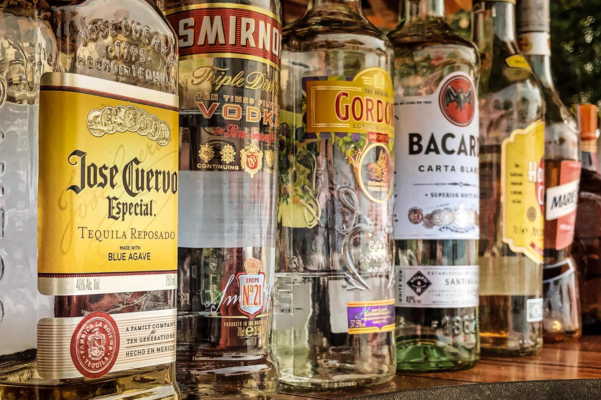 Varias bebidas espirituosas y licores organizadas en un bar.