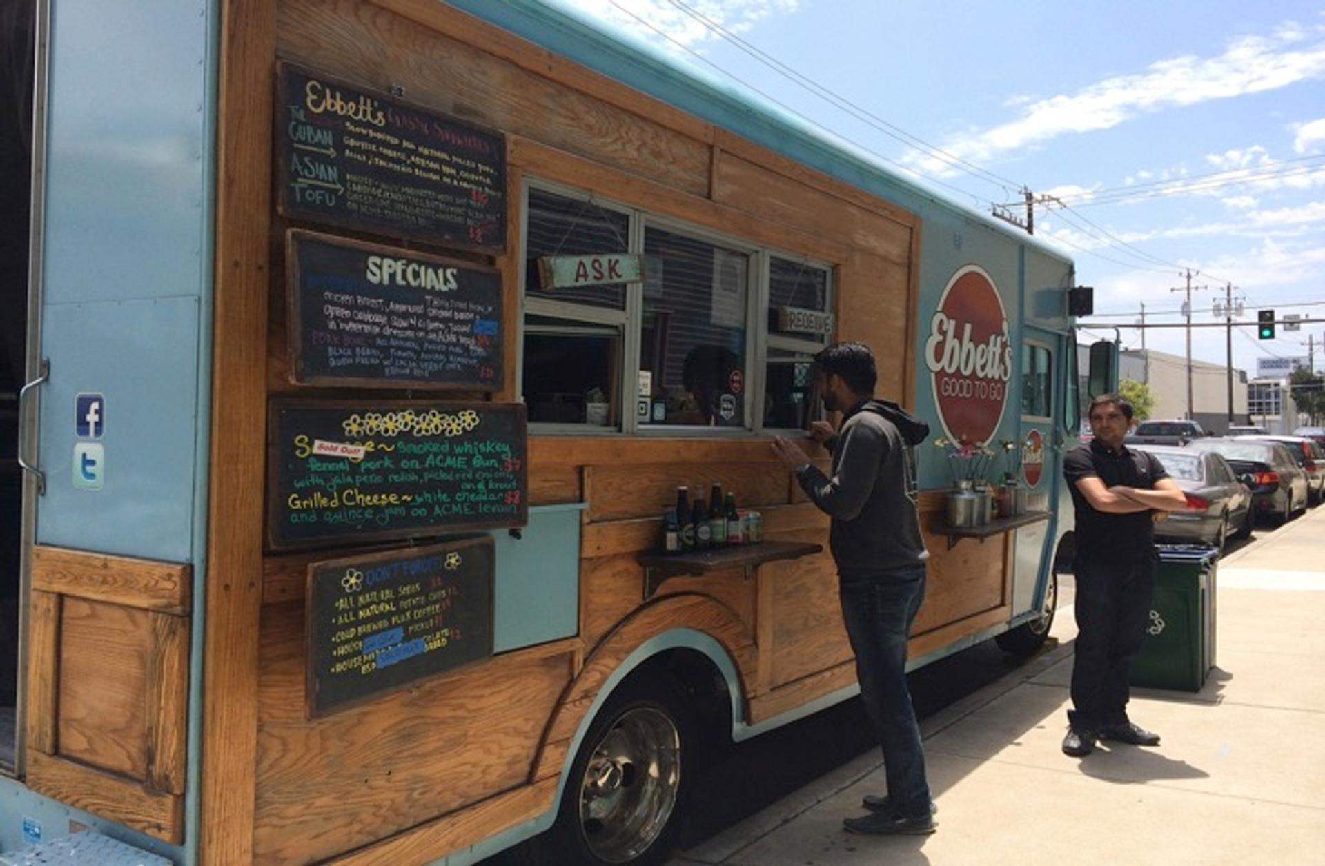 camión de comida o food truck estacionado y persona ordenando comida a través de la ventana