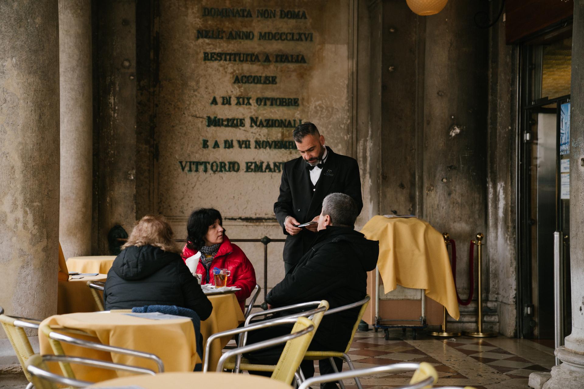 Chelner vorbind cu clienții restaurantului