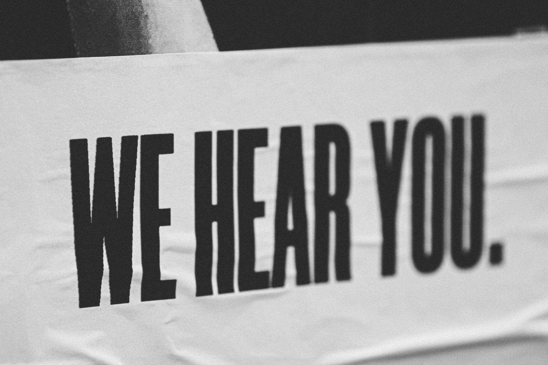 Poster que dice 'we hear you' que significa te escuchamos en inglés 