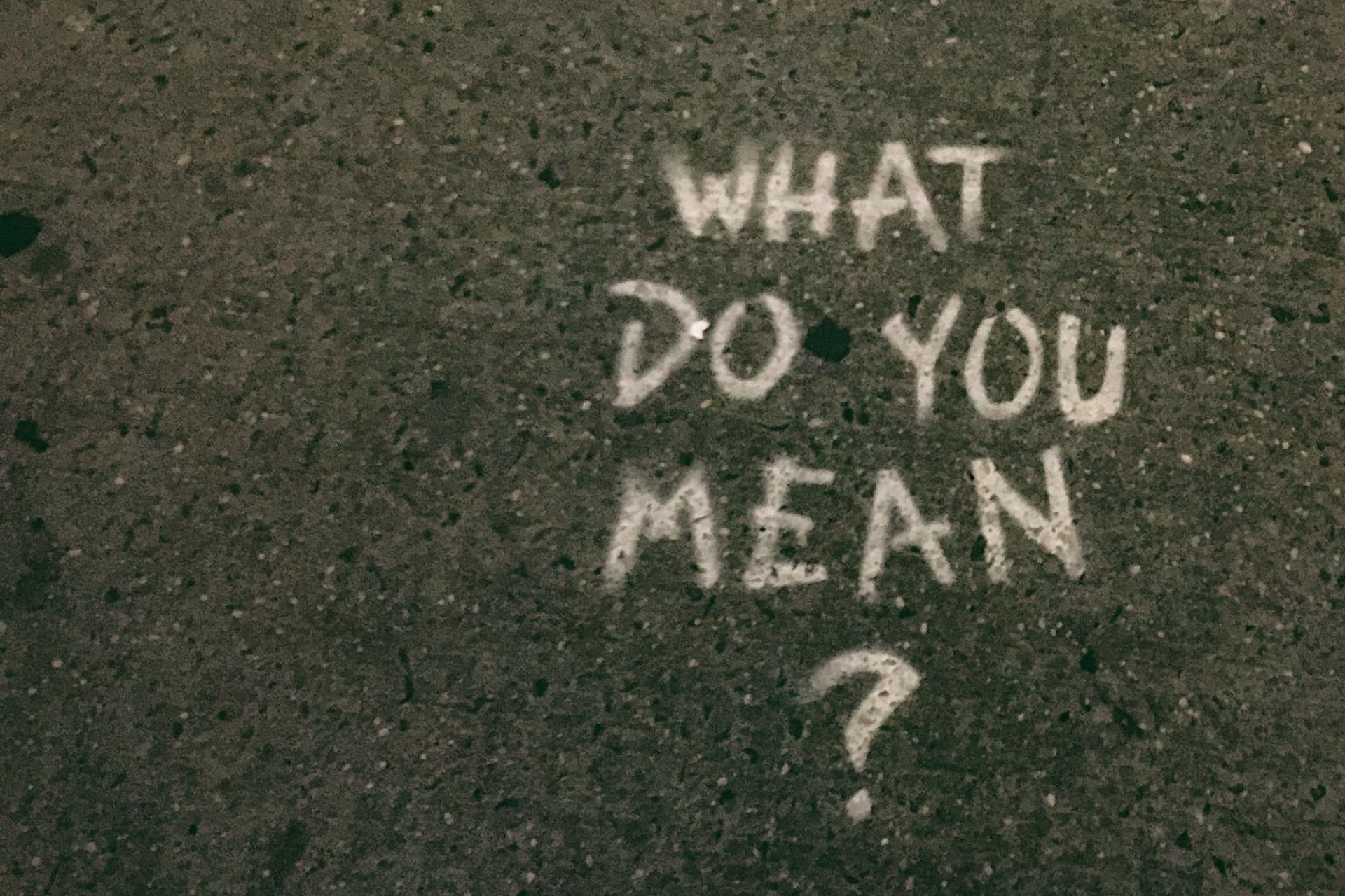  A qué te refieres? en inglés con el signo de interrogación escrito sobre asfalto con tiza