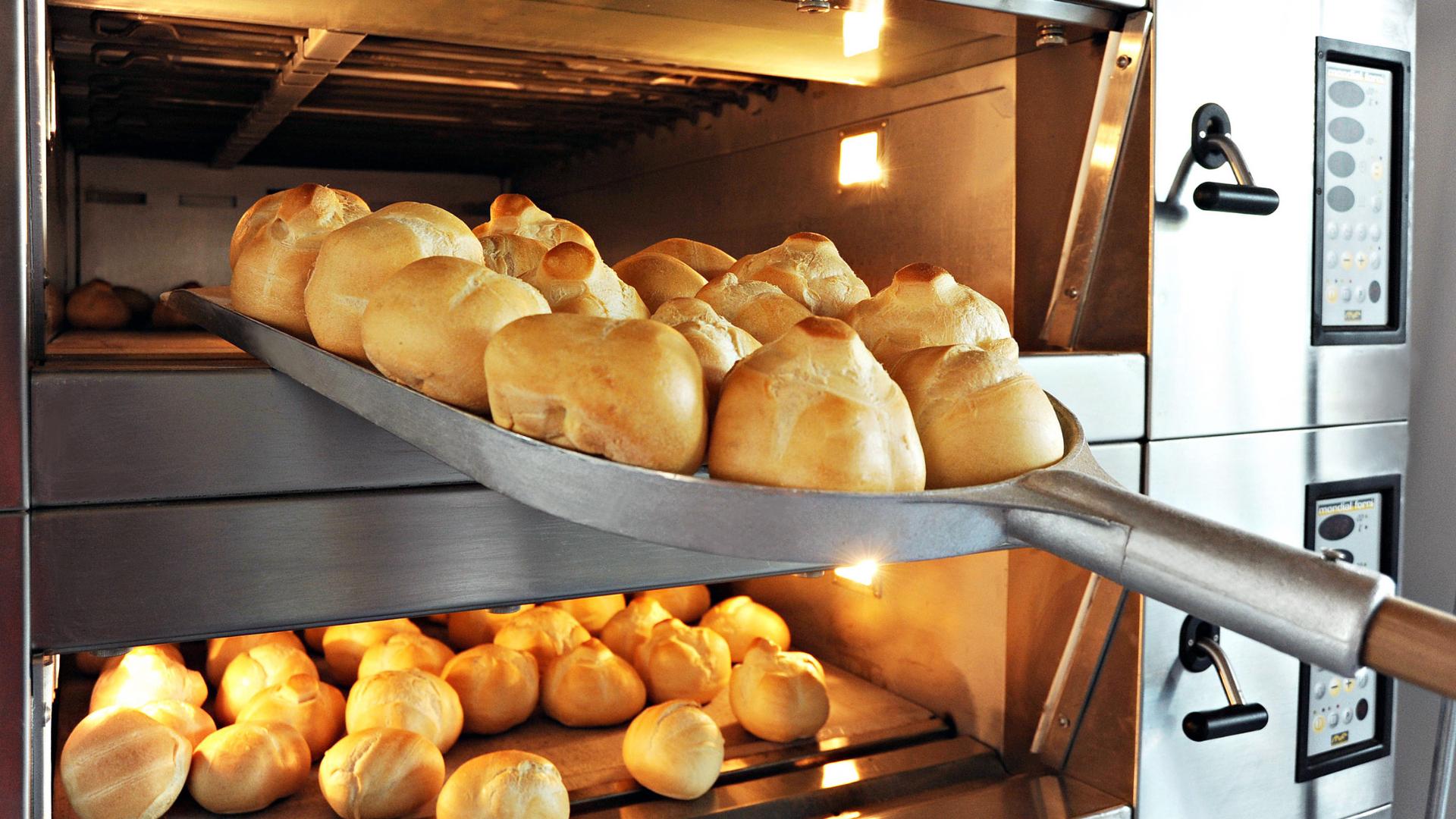 person taking bread out of a bakery's oven