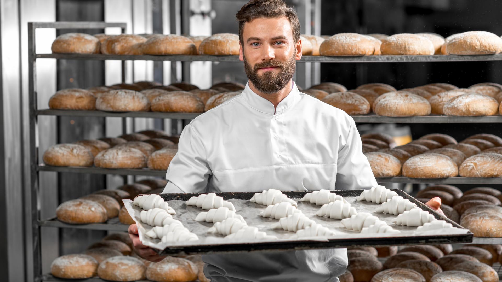 expert baker holding tray with croissants