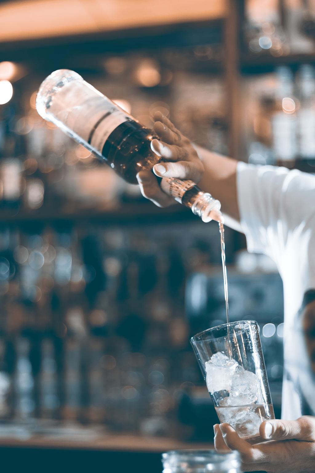 barteder pouring drink in the glass