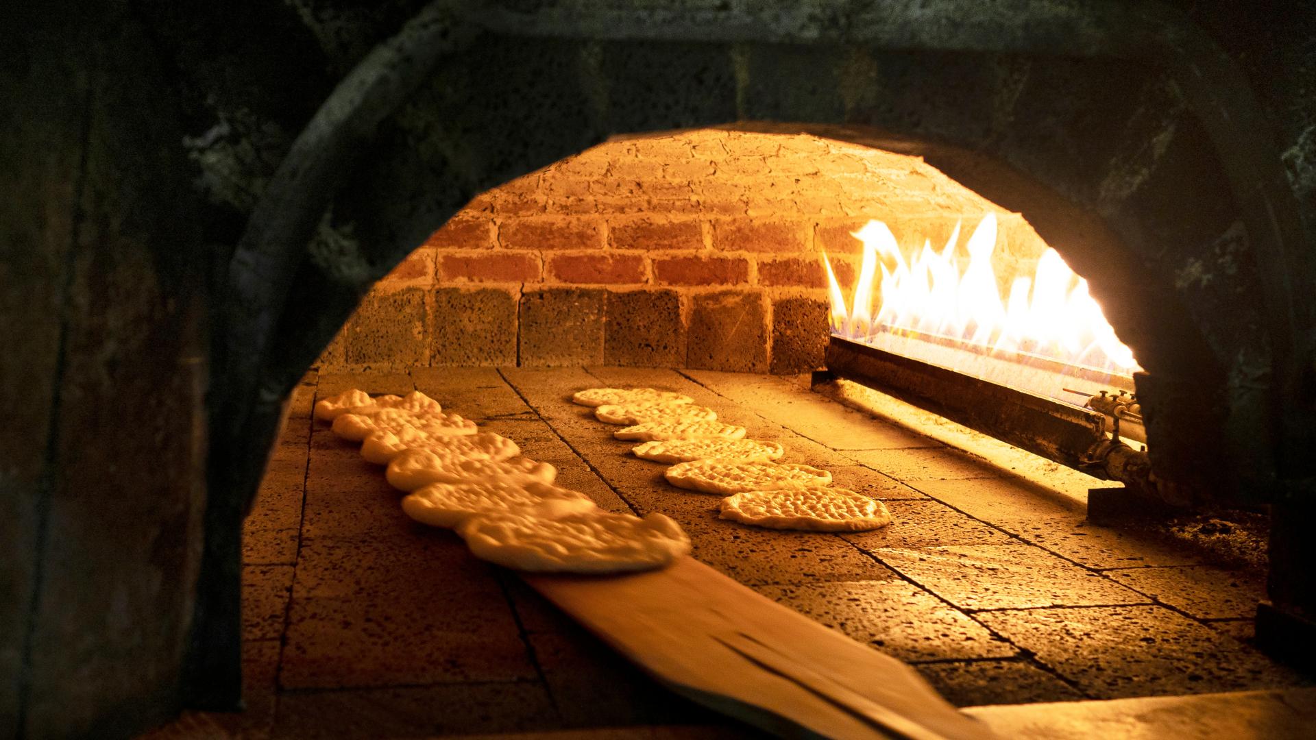 several pizzas inside a lit brick oven
