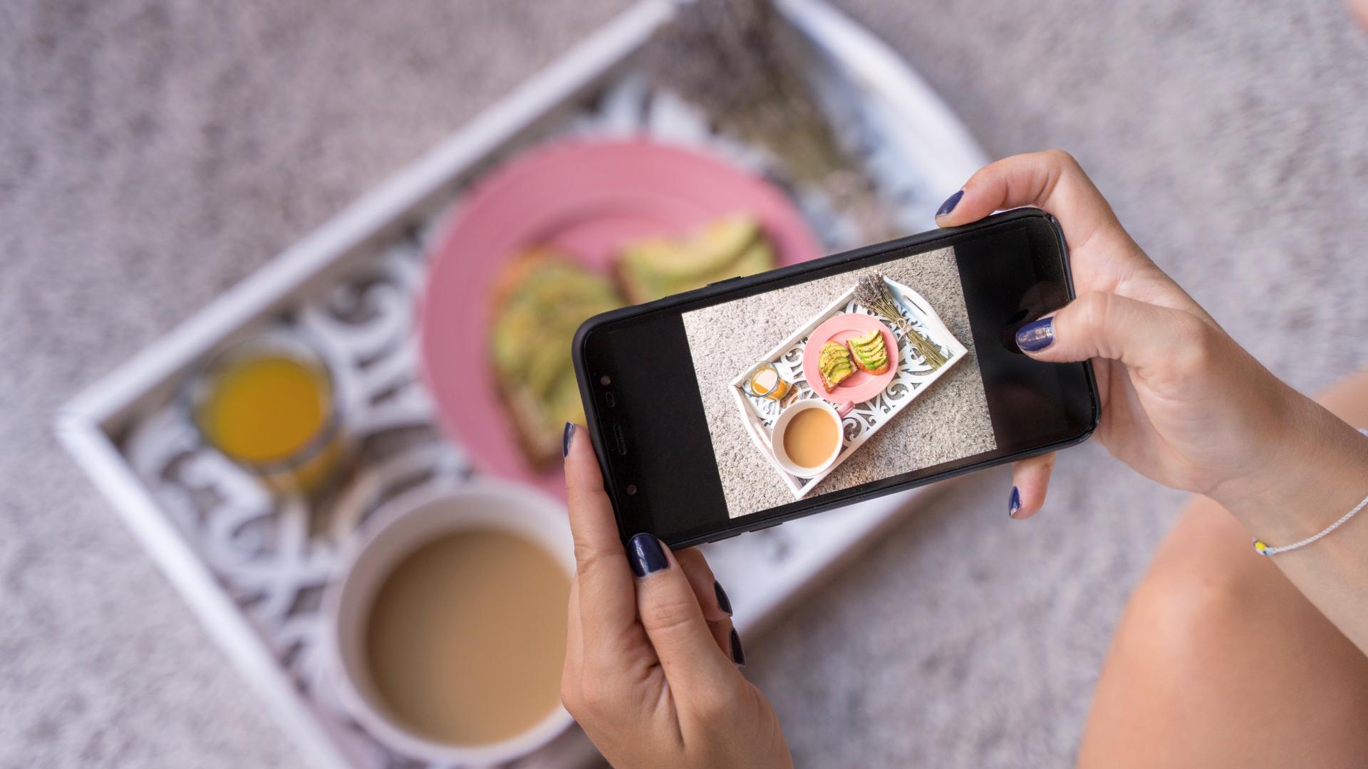 mujer tomando una foto de su comida en un restaurante