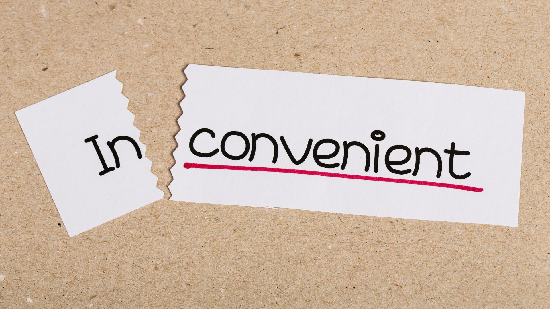 Word inconvenient written on paper that has been torn to show the word convenient only