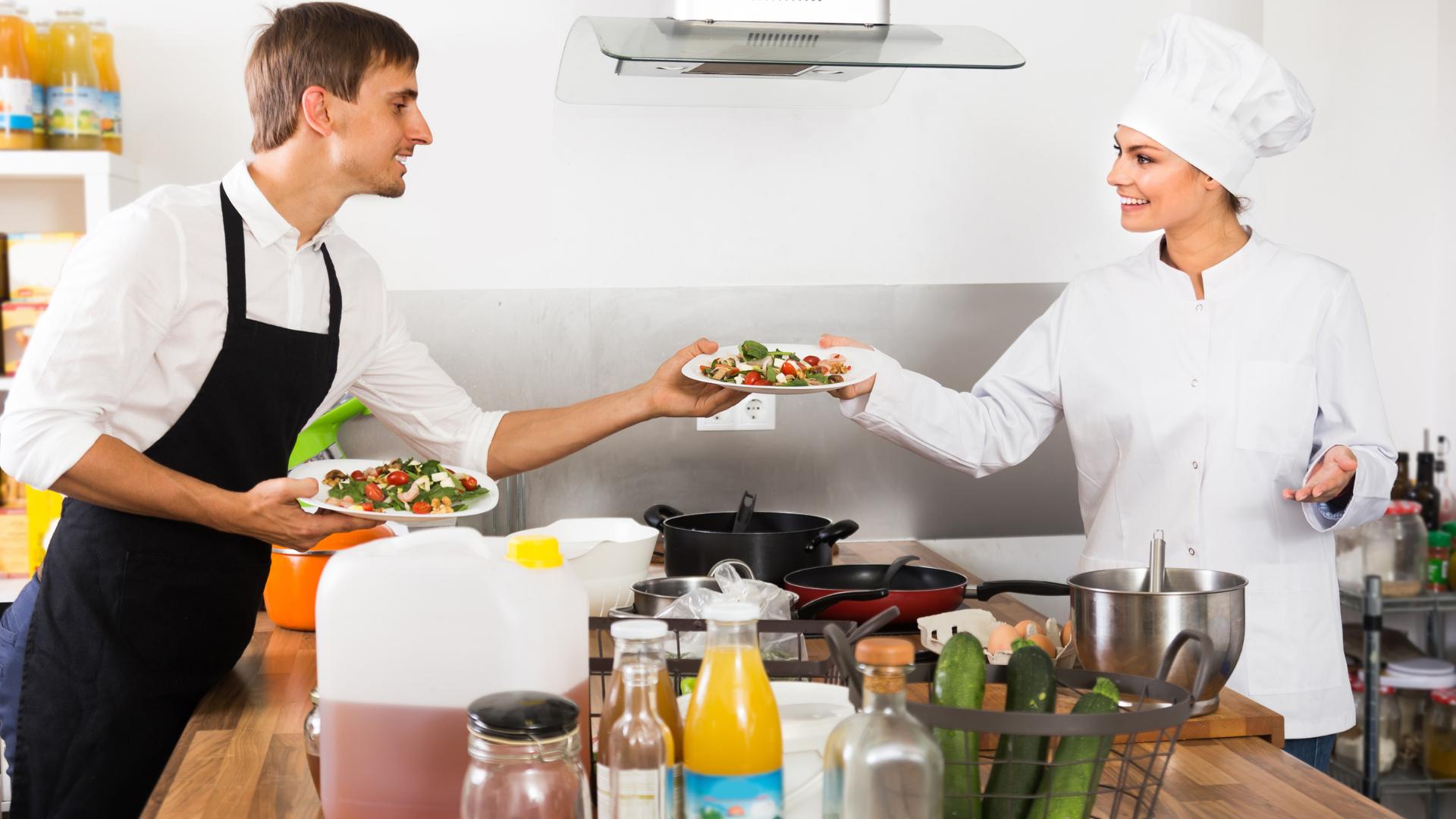 Koch, der dem Kellner Essen liefert, damit er die Kunden bedienen kann