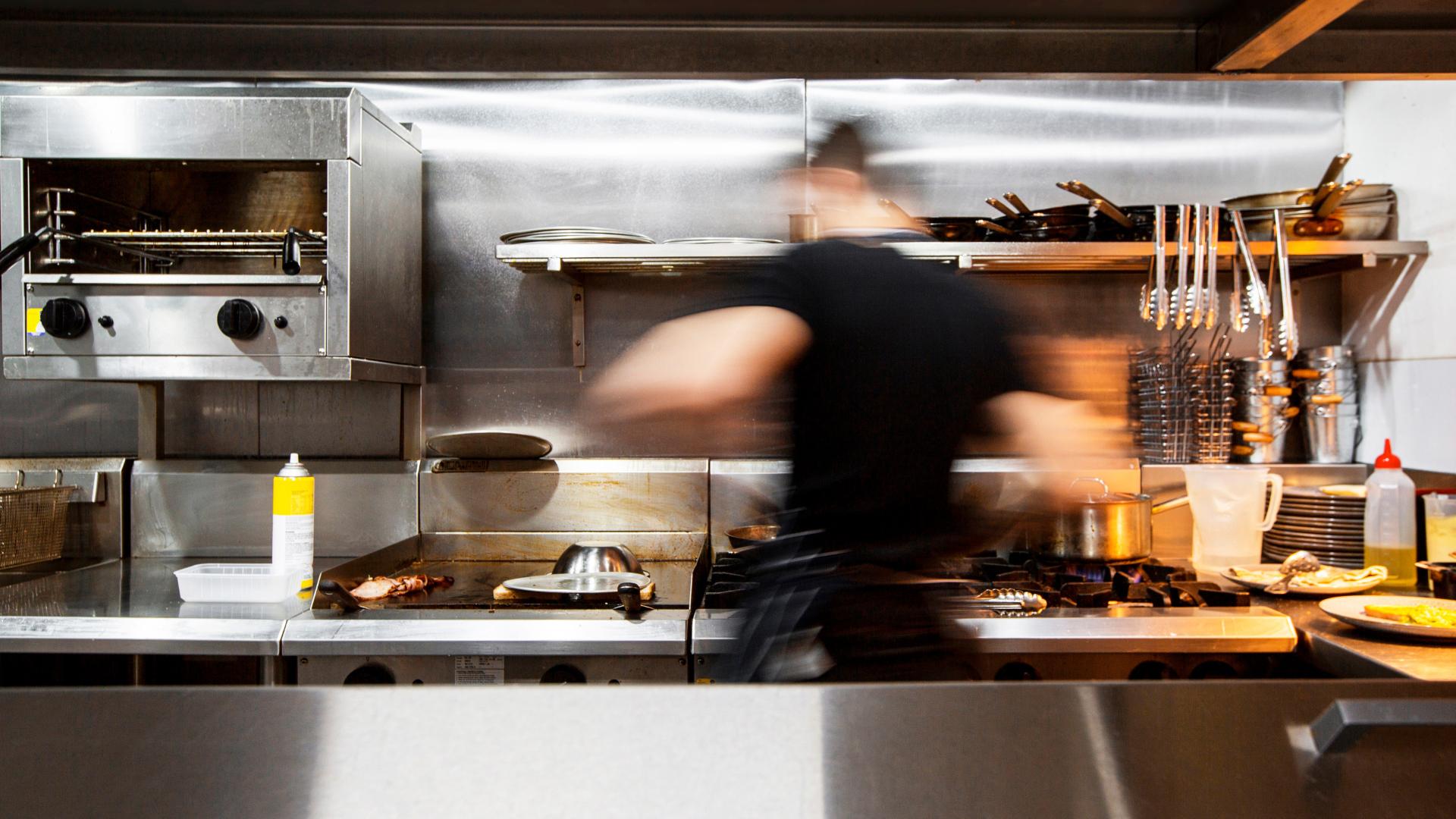 cook working really fast inside a restaurant's kitchen