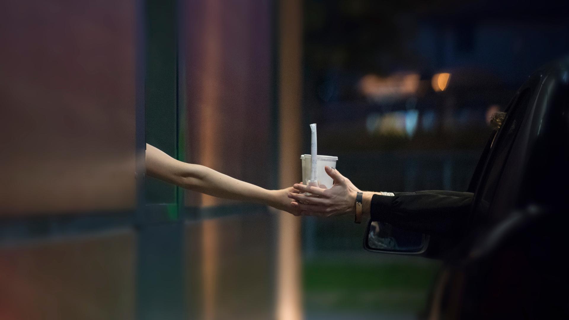 cliente que recibe su pedido a través de la ventana del auto en un drive thru