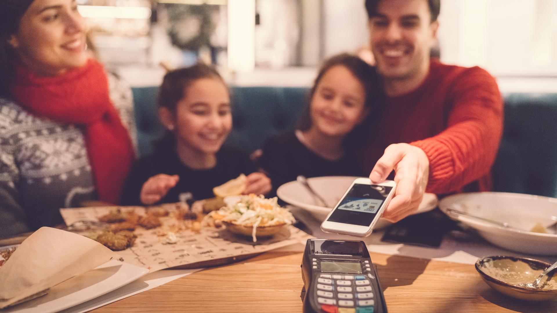 Familie bezahlt nach dem Essen in einem Restaurant an einem POS