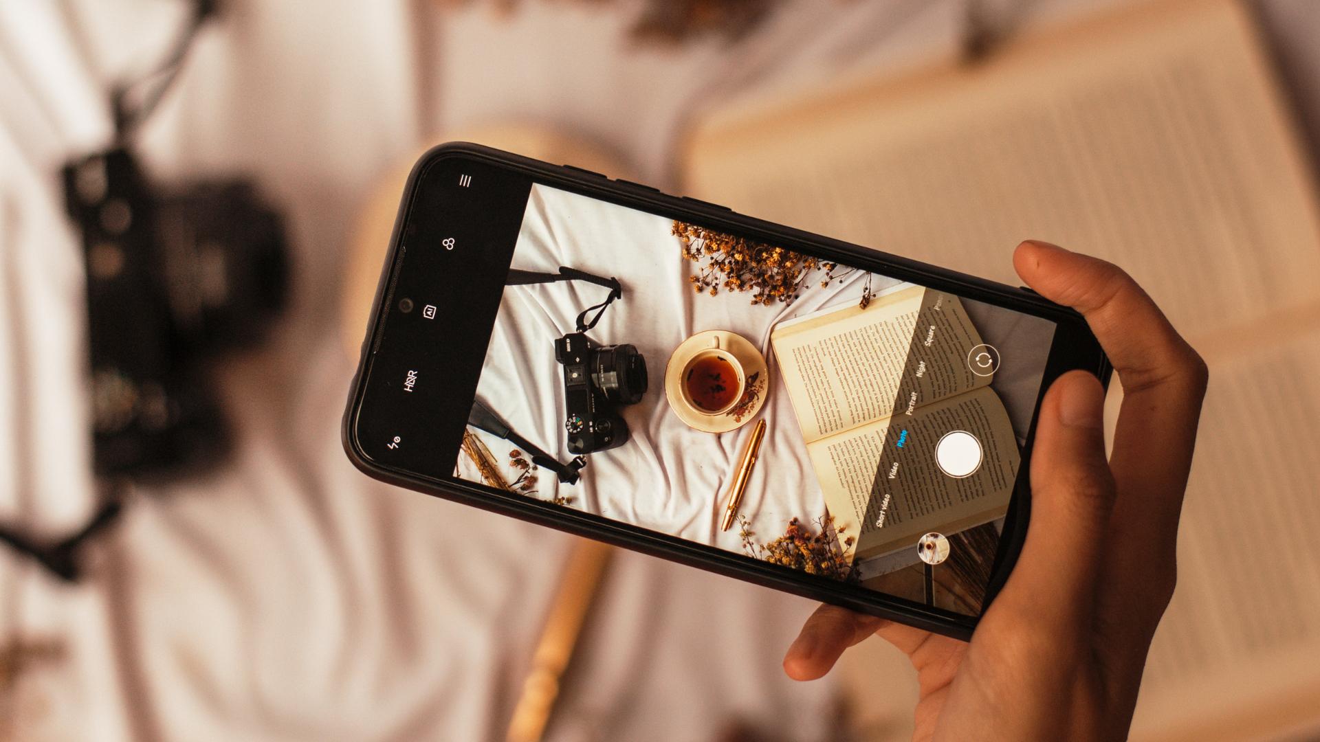 fotografia telefônica de uma câmera, diário e chá para simbolizar o domínio da mídia visual