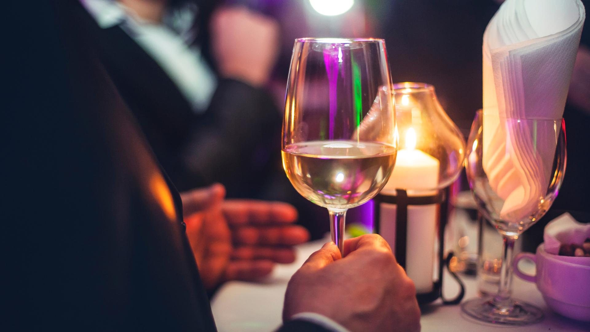 person holding glass with wine at a restaurant event