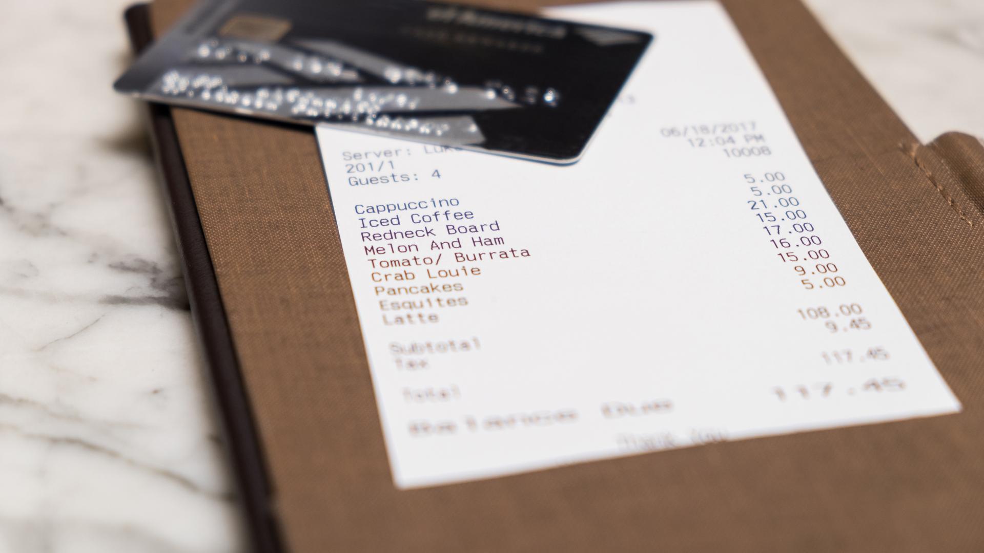 Restaurantrechnung und eine Kreditkarte darüber, um die durchschnittliche Restaurantrechnung zu symbolisieren