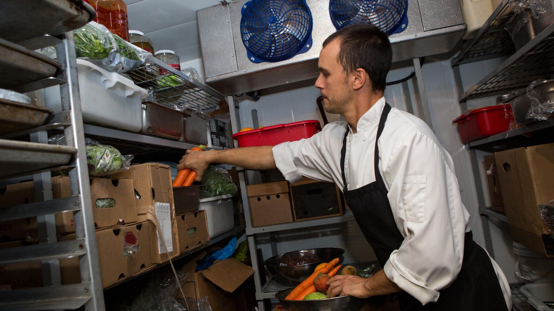 cocinero dentro de una cámara frigorífica reuniendo ingredientes