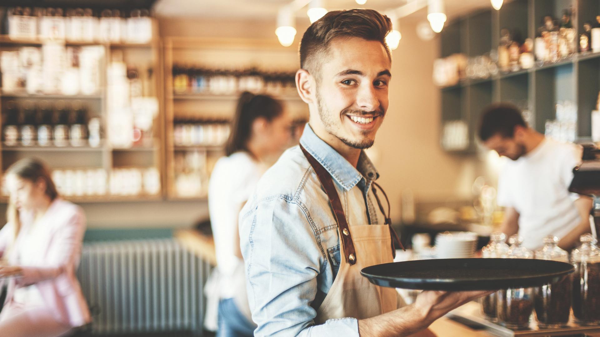 cameriere sorridente davanti al bar del ristorante